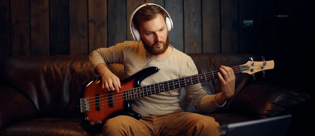 Ein Mann mit weißen Kopfhörern mit einer E-Gitarre