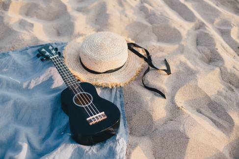 Schwarze Ukulele auf einer Decke im Sand